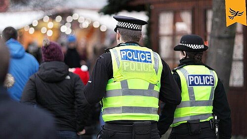 Two police officers walk down a street